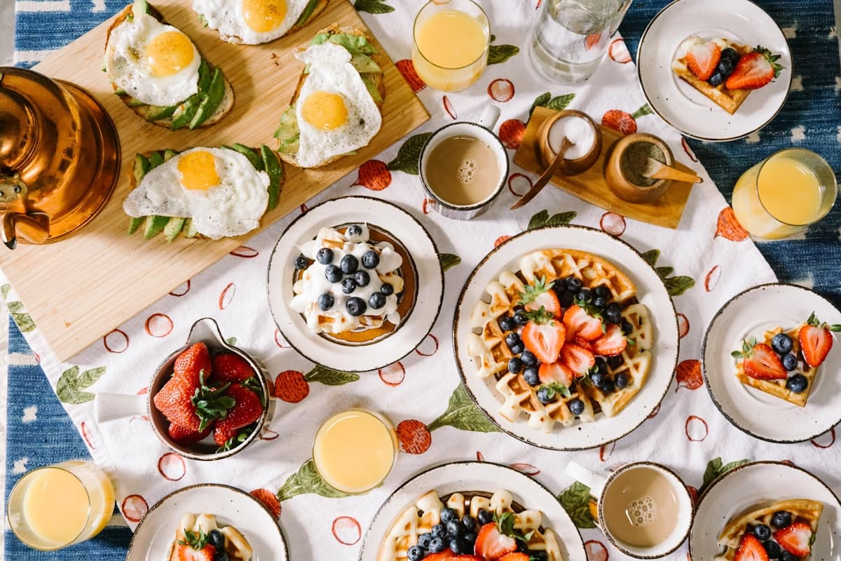 A sunlit brunch spread with fresh pastries, avocado toast, and coffee on a marble table
