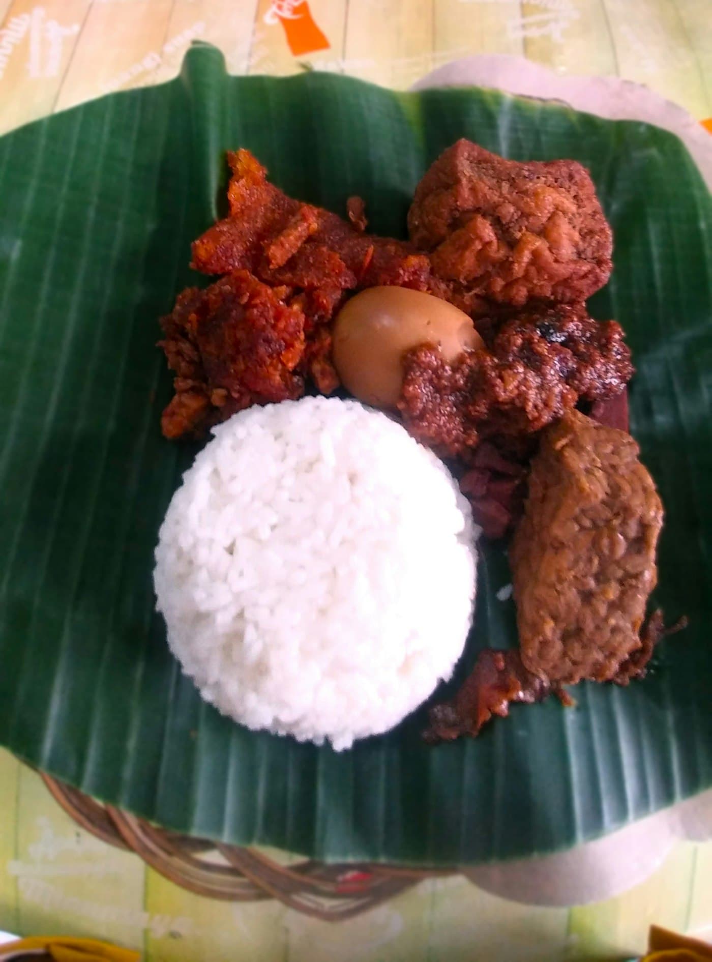 An Indonesian street-food spread on a banana leaf with rice and side dishes
