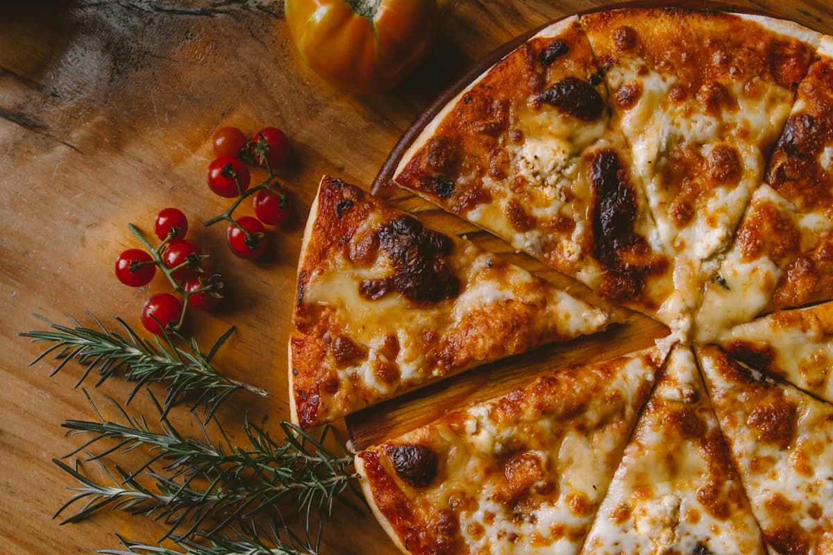 A blistered thin-crust pizza on a restaurant table with wine glasses in a warm dining room