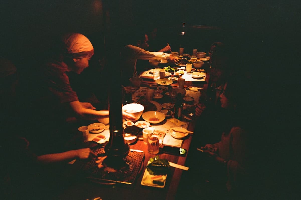 A lively group dinner at a New York City restaurant with plates of food covering the table