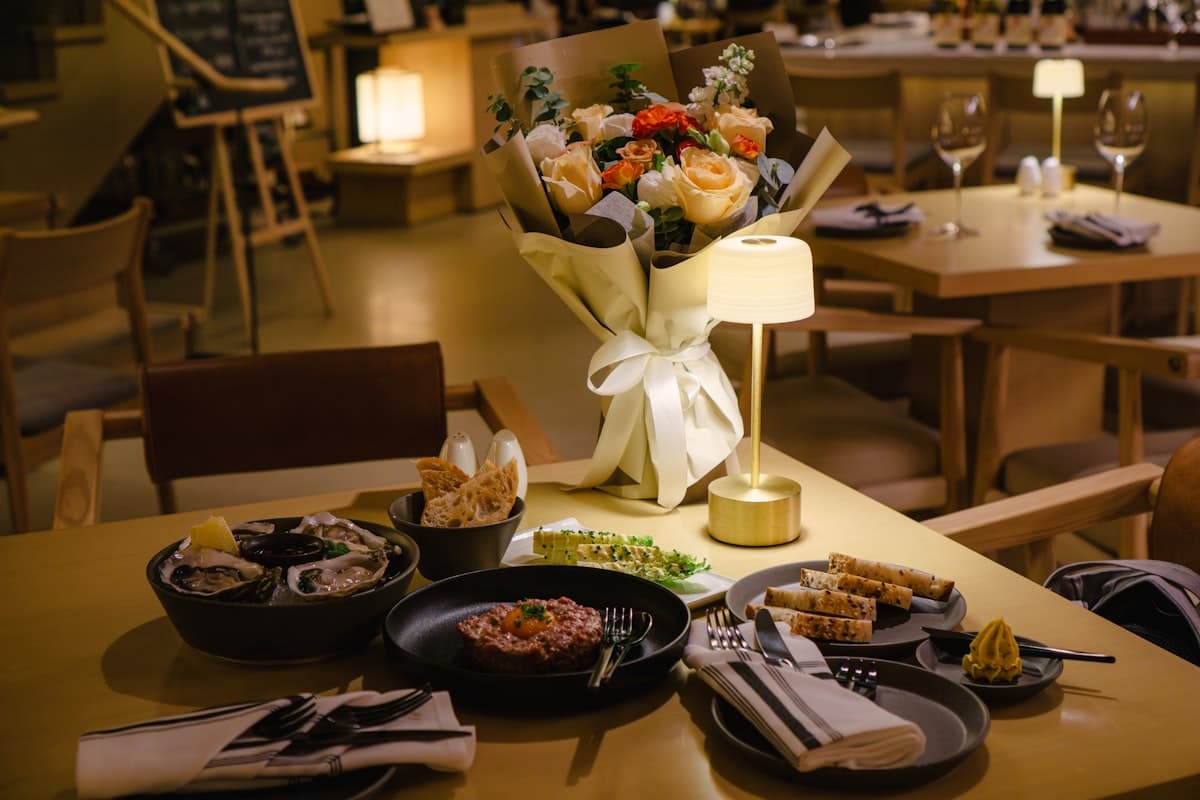 An elegant seafood restaurant table with oysters, cocktails, and warm lamplight