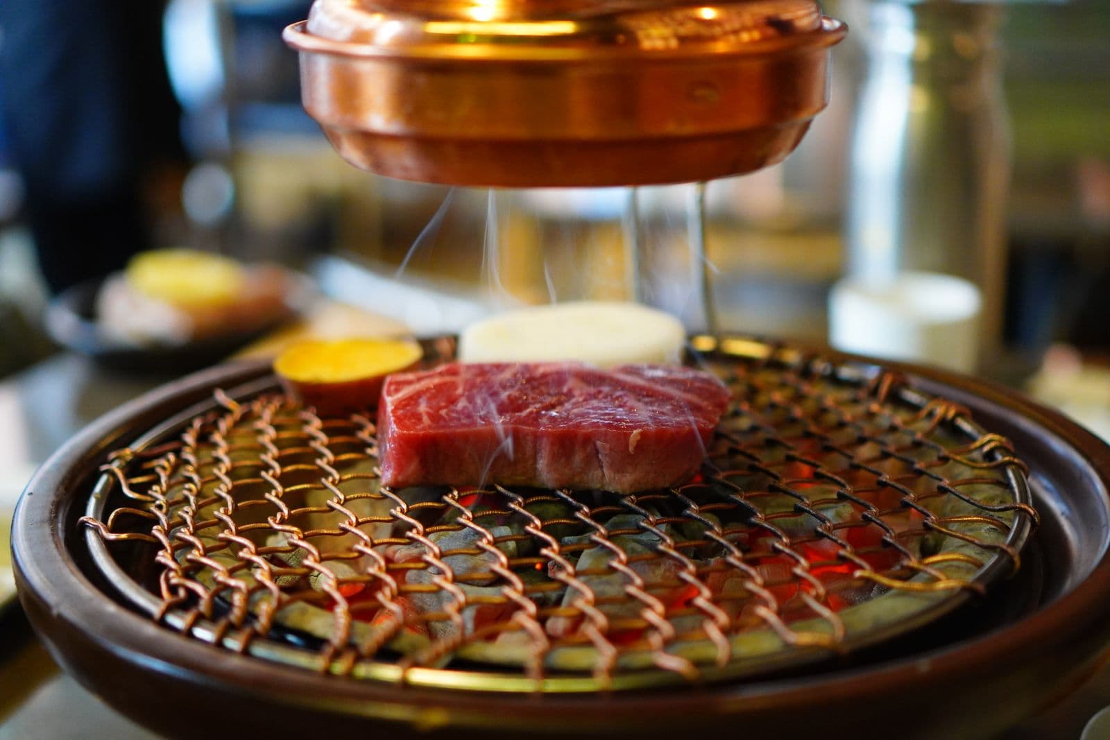 A thick steak cooking over a tabletop Korean barbecue grill