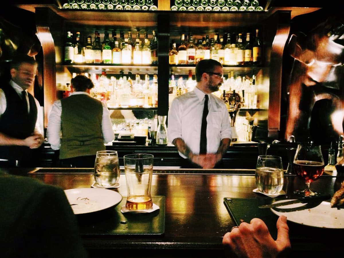 A lively bar scene with drinks, warm light, and a social late-dinner atmosphere