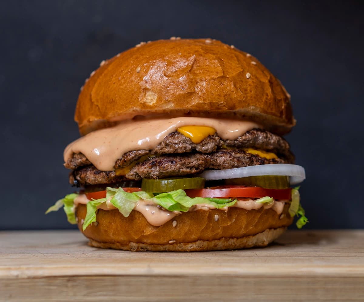 A stacked smashburger with crispy patties in a lively casual dining setting