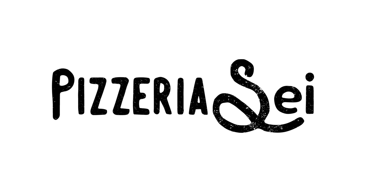 A blistered wood-fired pizza on a table beside wine glasses in a cozy restaurant
