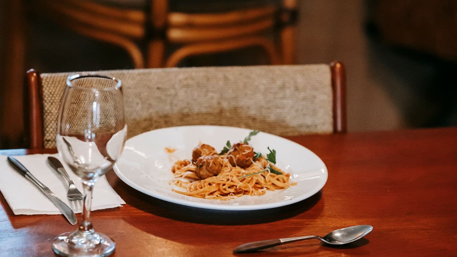 Plates of pasta and drinks set across a warmly lit restaurant table